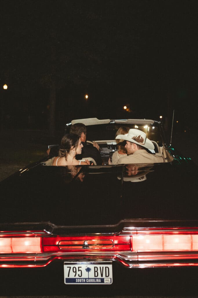 Couple sharing a quiet moment in a vintage convertible at night after a wedding celebration