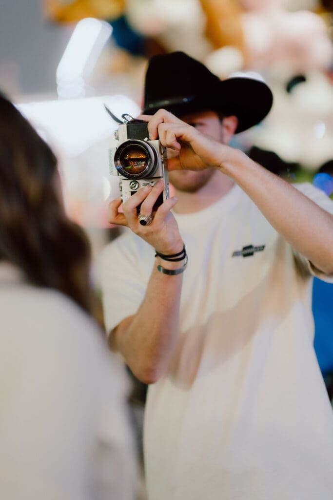 Photographer raises a film camera while documenting a candid moment, reflecting the personal, artistic approach couples may seek when comparing wedding photographers in Charleston SC.