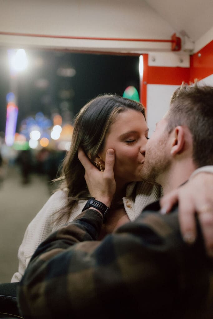 Couple shares an intimate kiss inside a lively arcade, blending spontaneous emotion with documentary style Charleston engagement photography.