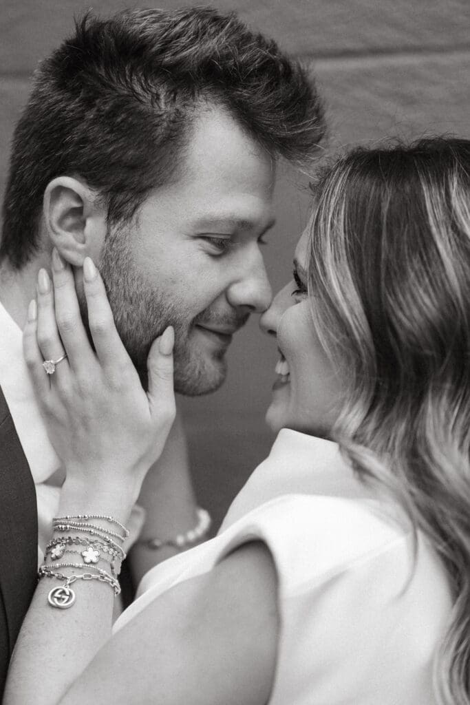 Black and white close up of an engaged couple leaning toward each other as she gently touches his face, an intimate moment from Charleston engagement photography.