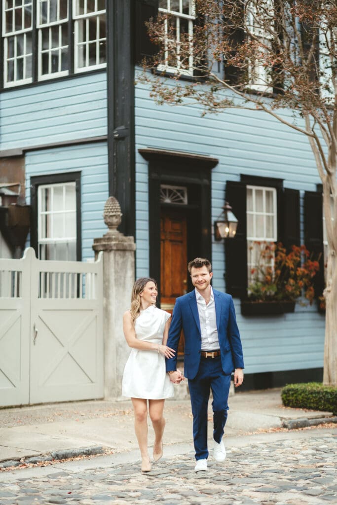 Couple holding hands along a cobblestone street in historic Charleston, SC