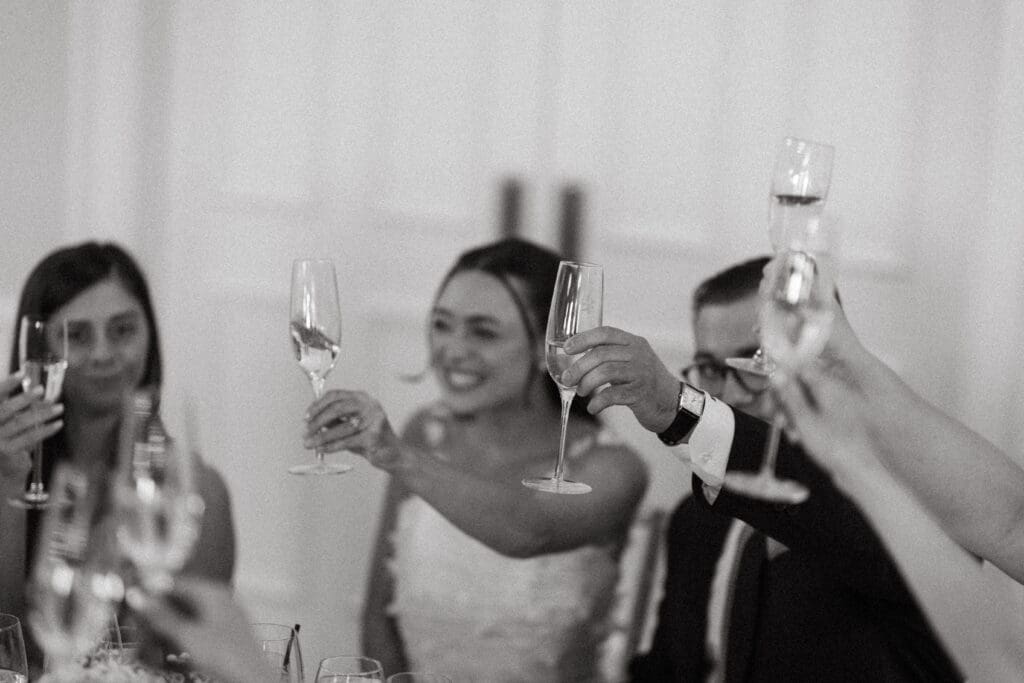 Bride and guests raising champagne glasses during a wedding celebration