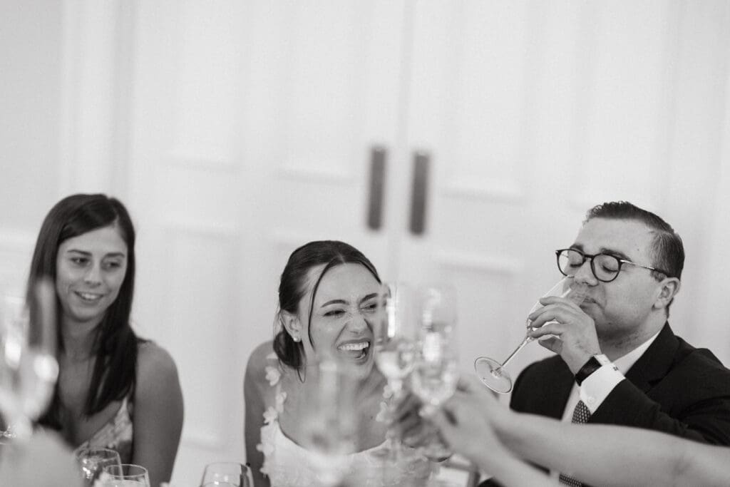 Bride smiles during a reception toast at a candlelit table, preserving an unscripted moment through editorial Charleston wedding photography.
