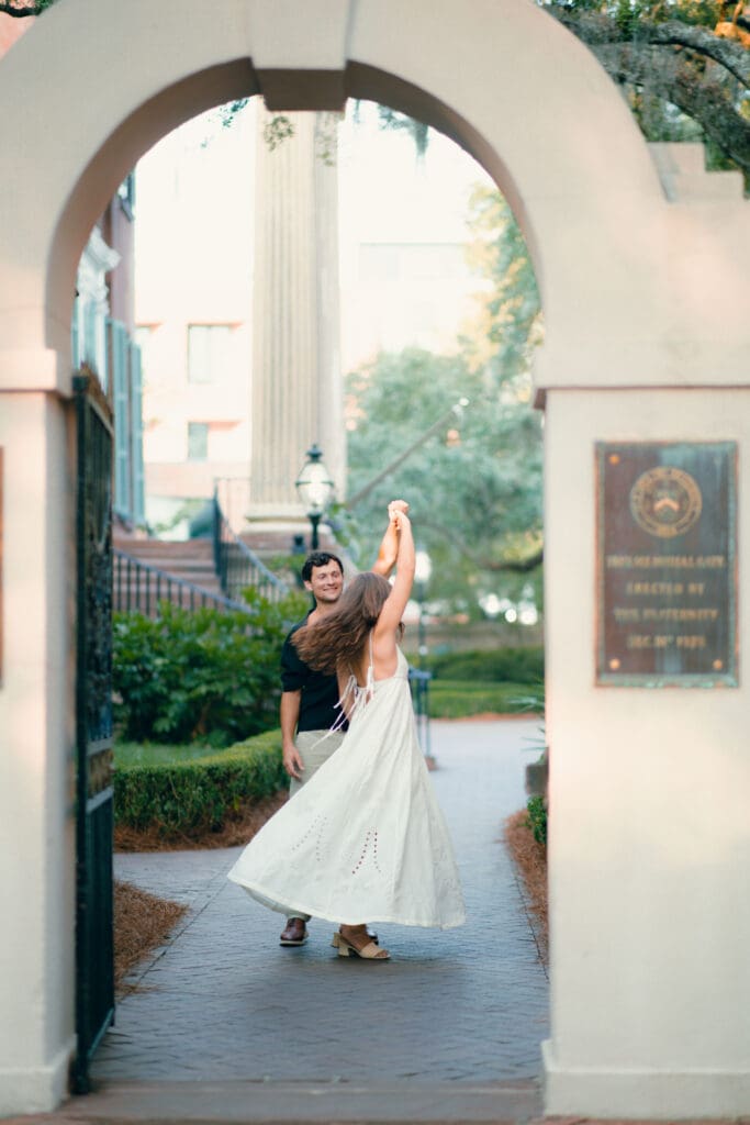 Bride twirls beneath an arched entryway, her dress moving softly in the natural light, an elegant example of Charleston SC bridal photography.
