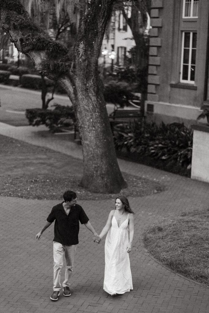 Black-and-white photograph of a couple holding hands on a brick pathway