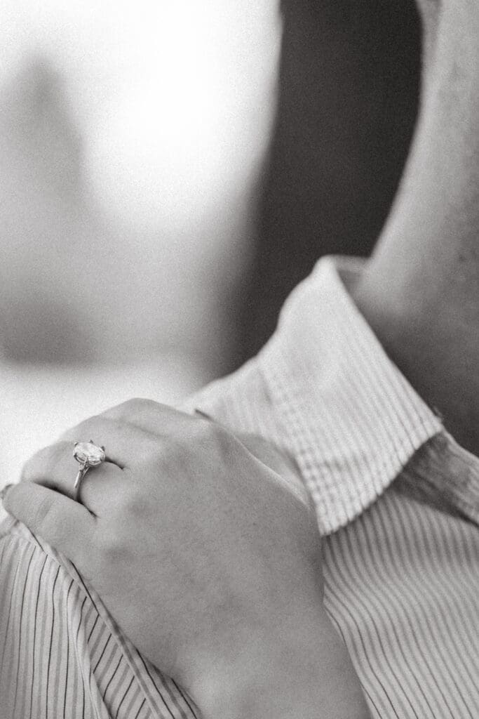 Close up of an engagement ring resting on a hand against soft fabric, highlighting the refined detail photography offered by Charleston SC wedding photographers.