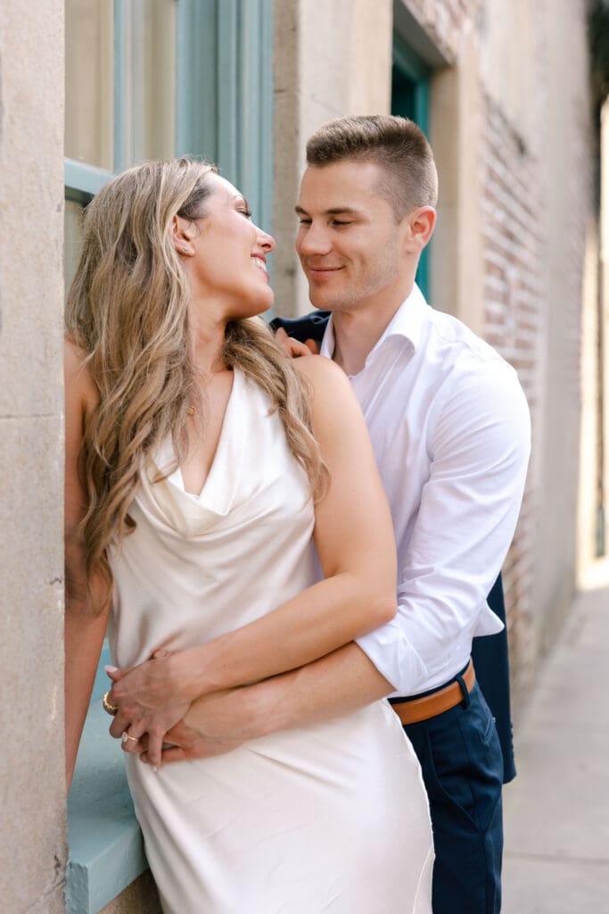 Couple sharing an intimate embrace beside a historic building in Charleston, SC