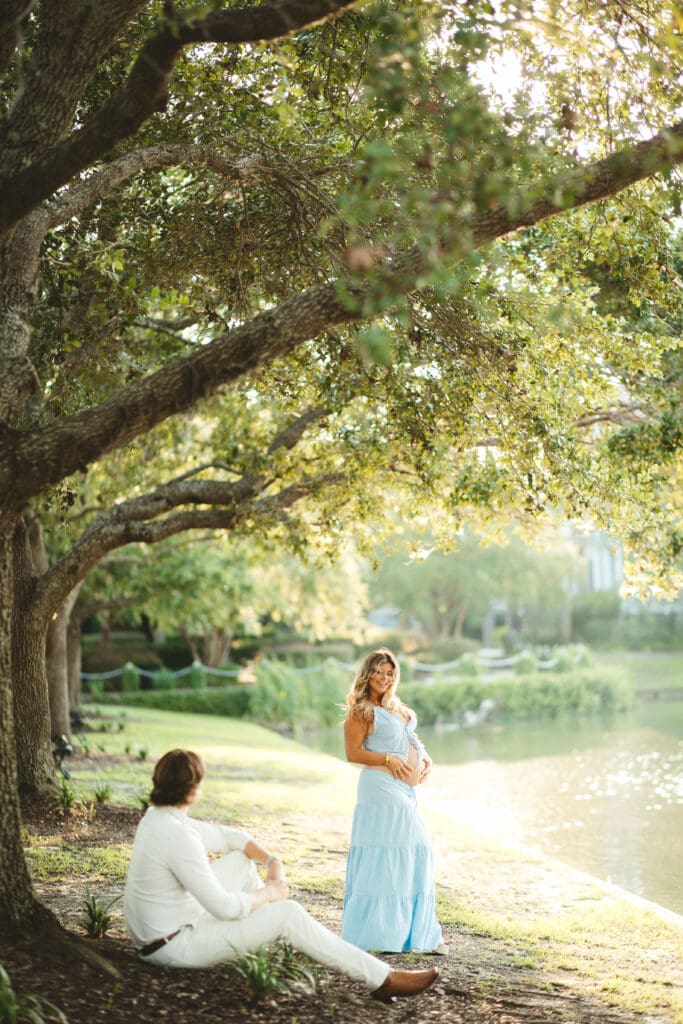 Couple shares a quiet moment beneath sprawling oak branches beside the water, highlighting the natural beauty surrounding an outdoor wedding venue Charleston SC.