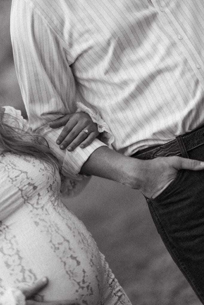 Black and white detail of an expectant couple holding hands over the mother’s baby bump, an intimate moment captured during a Mount Pleasant SC portrait session.